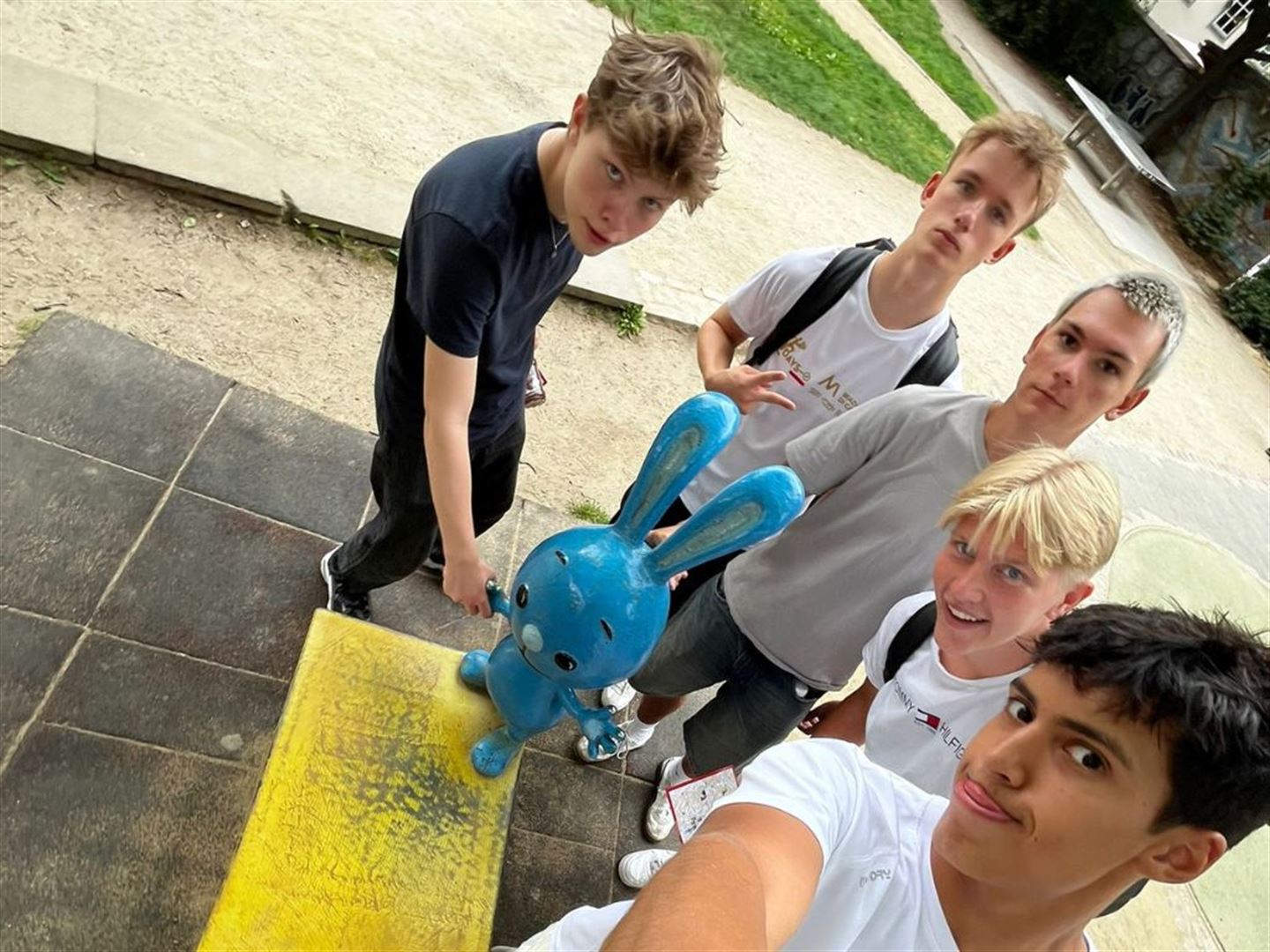 Fem gutter står rundt ein statue av ein blå kanin. 