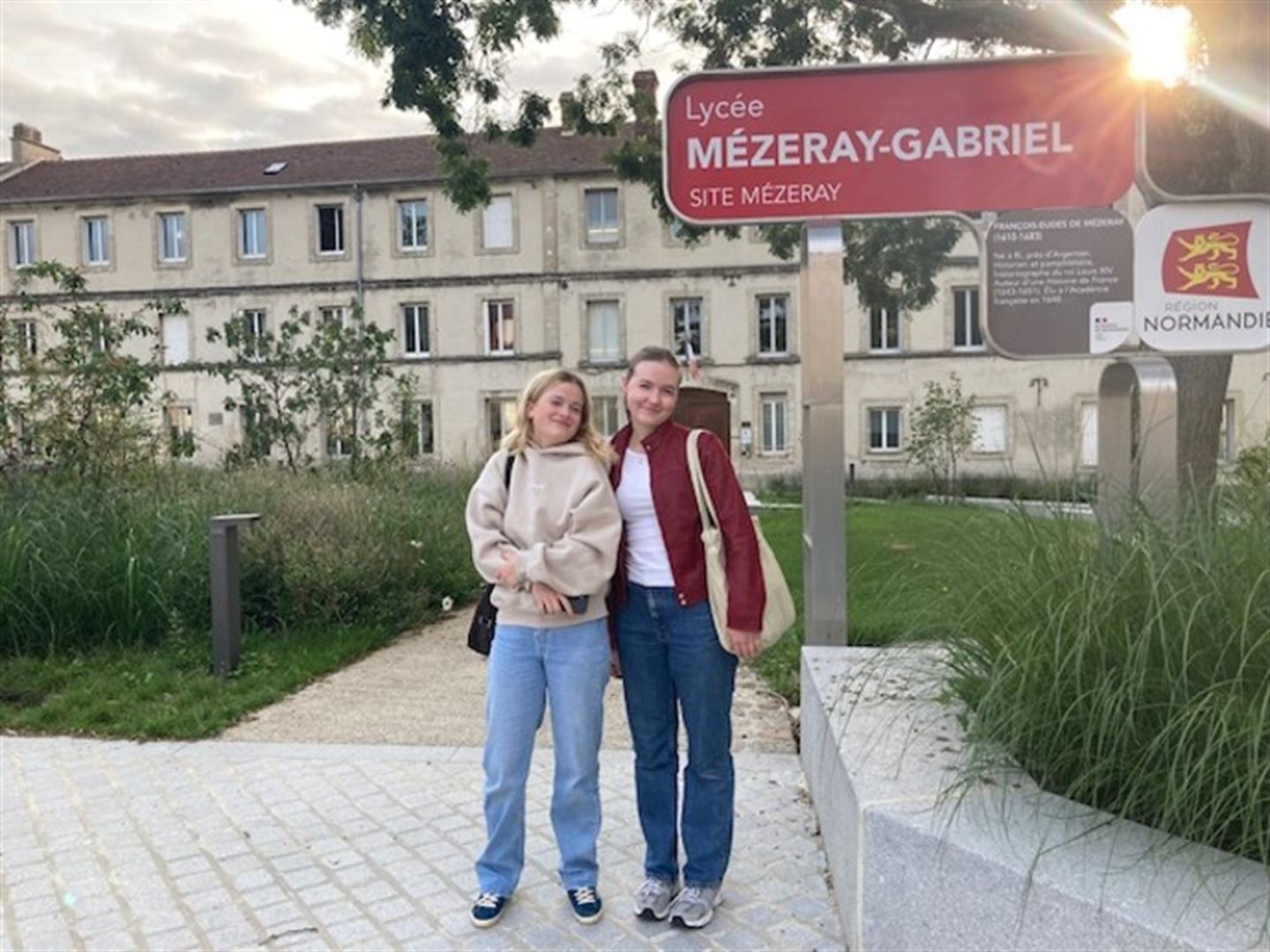 To jenter foran skilt på skulen. 