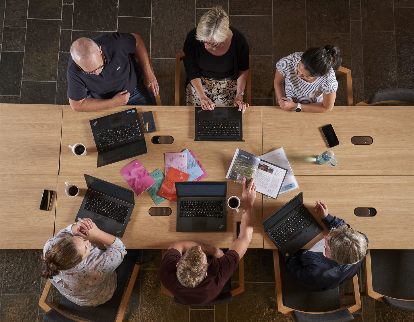 seks personer med pc sitter rundt et bord