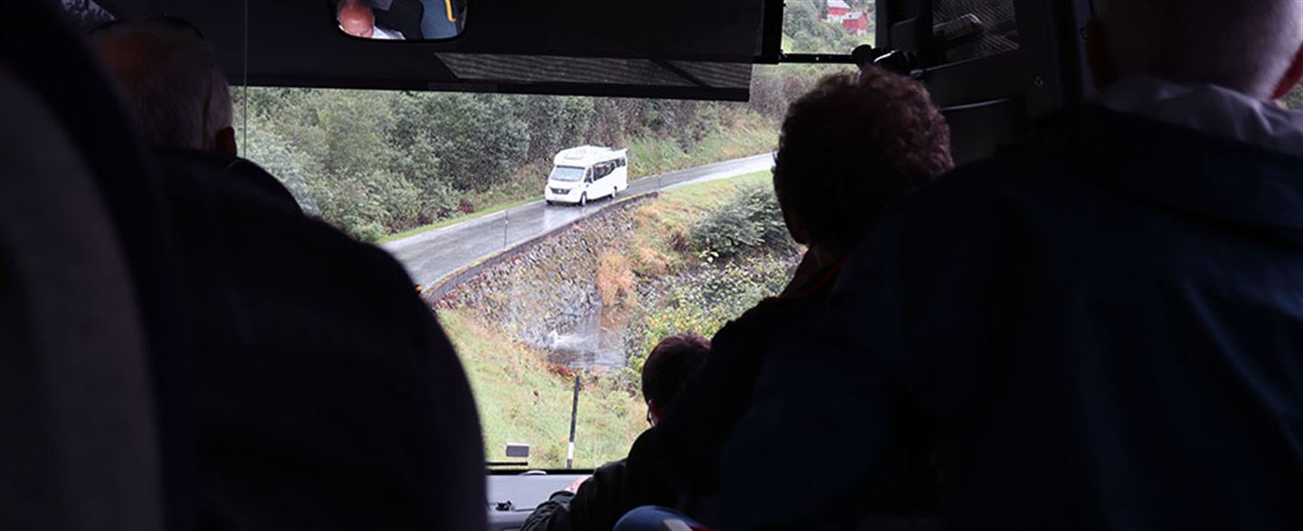 foto frå inni ein buss, der vi ser smal veg med møtande campingbil 