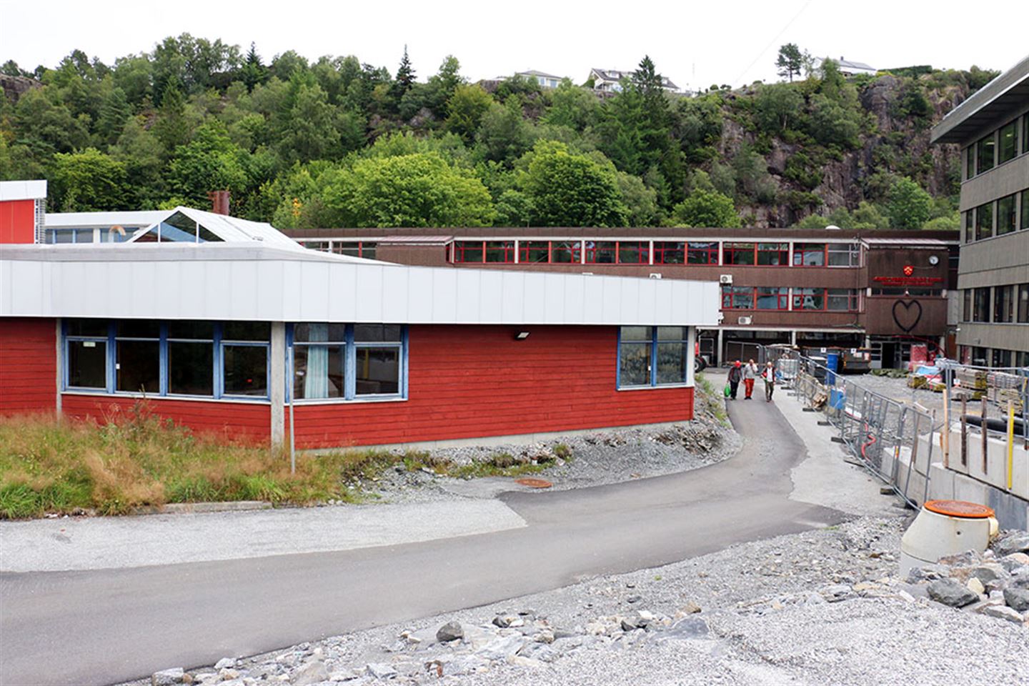 Den gamle verkstadhallen (i framgrunnen) skal rivast, og det skal byggast ein idrettshall på tomta. Den gamle skulen i bakgrunnen skal renoverast og takast i bruk som ein del av den nye skulen om eitt år. Helse- og oppvekstfag, tilrettelagt opplæring og vaksenopplæring skal halde til her. Foto: Bjarte Brask Eriksen/Vestland fylkeskommune