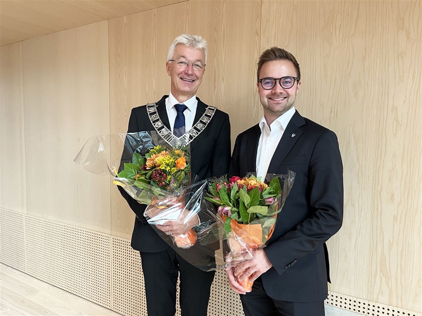 Foto av Jon Askeland og Stian Davies, begge i mørk dress og med kvar sin blomsterbukett i hendene.