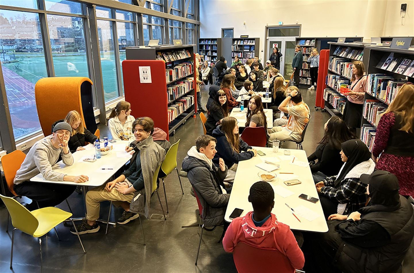 foto av ungdom som sit på bibliotek