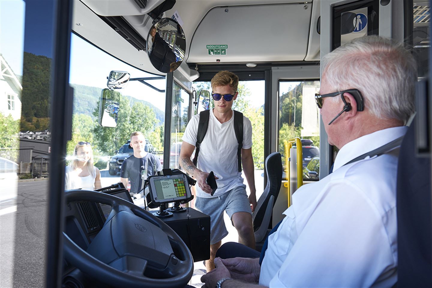 foto av bussjåfør og passasjer på veg inn i bussen