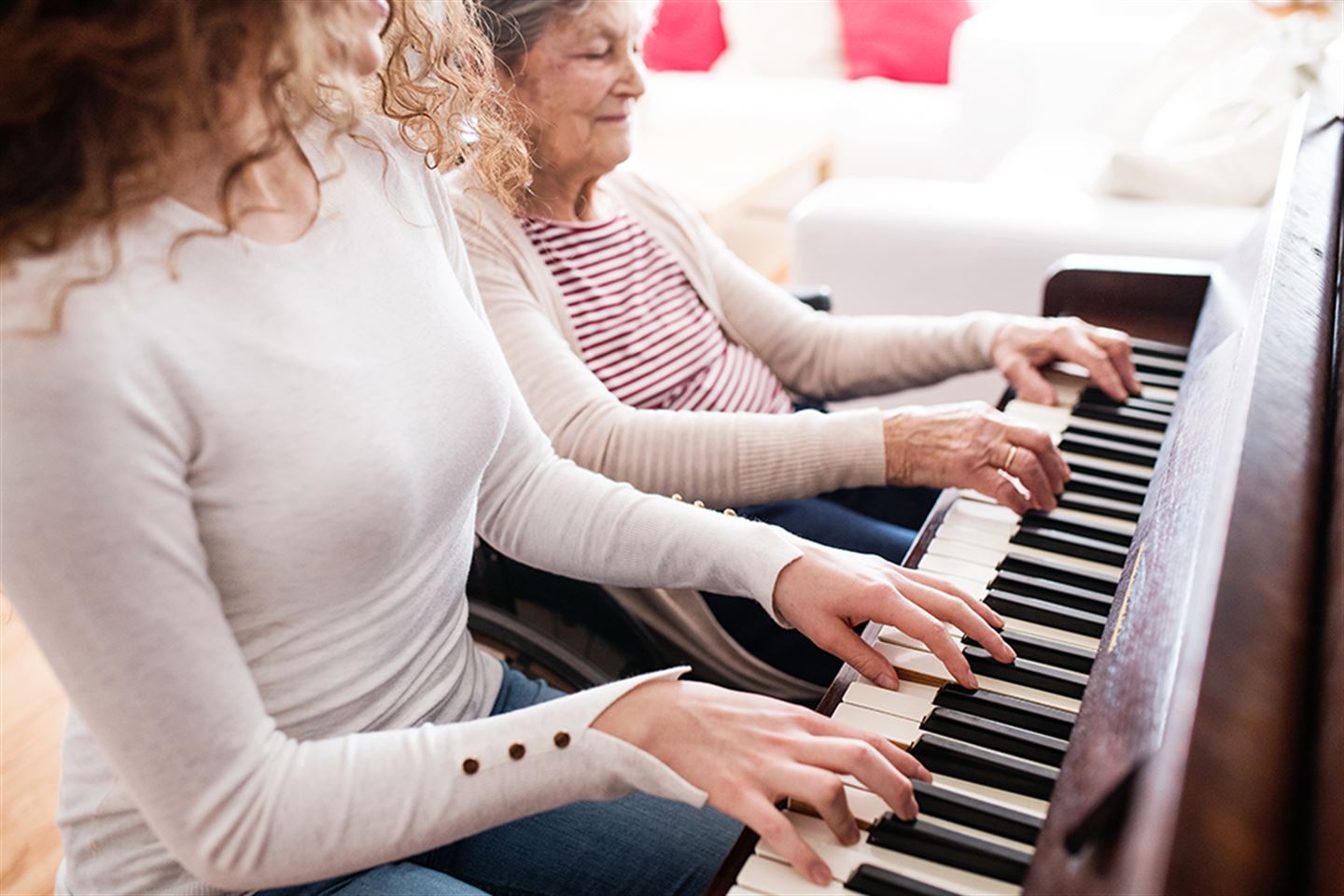 Ung og eldre kvinne spelar piano saman.