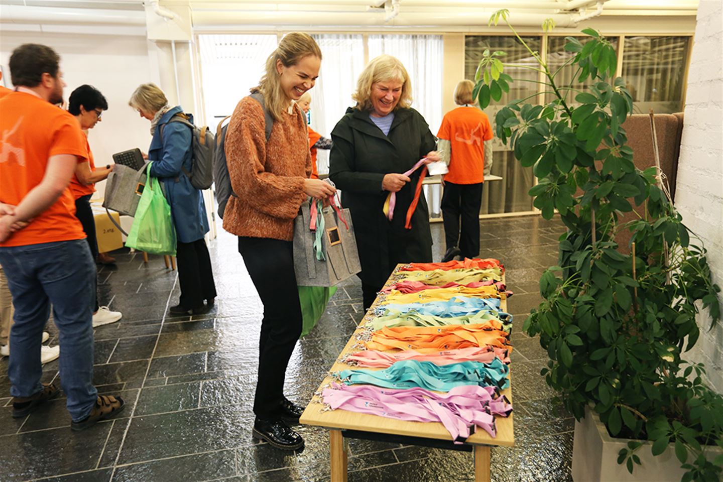 To kvinner står ved bord fullt av fargerike band til tilgangskort.