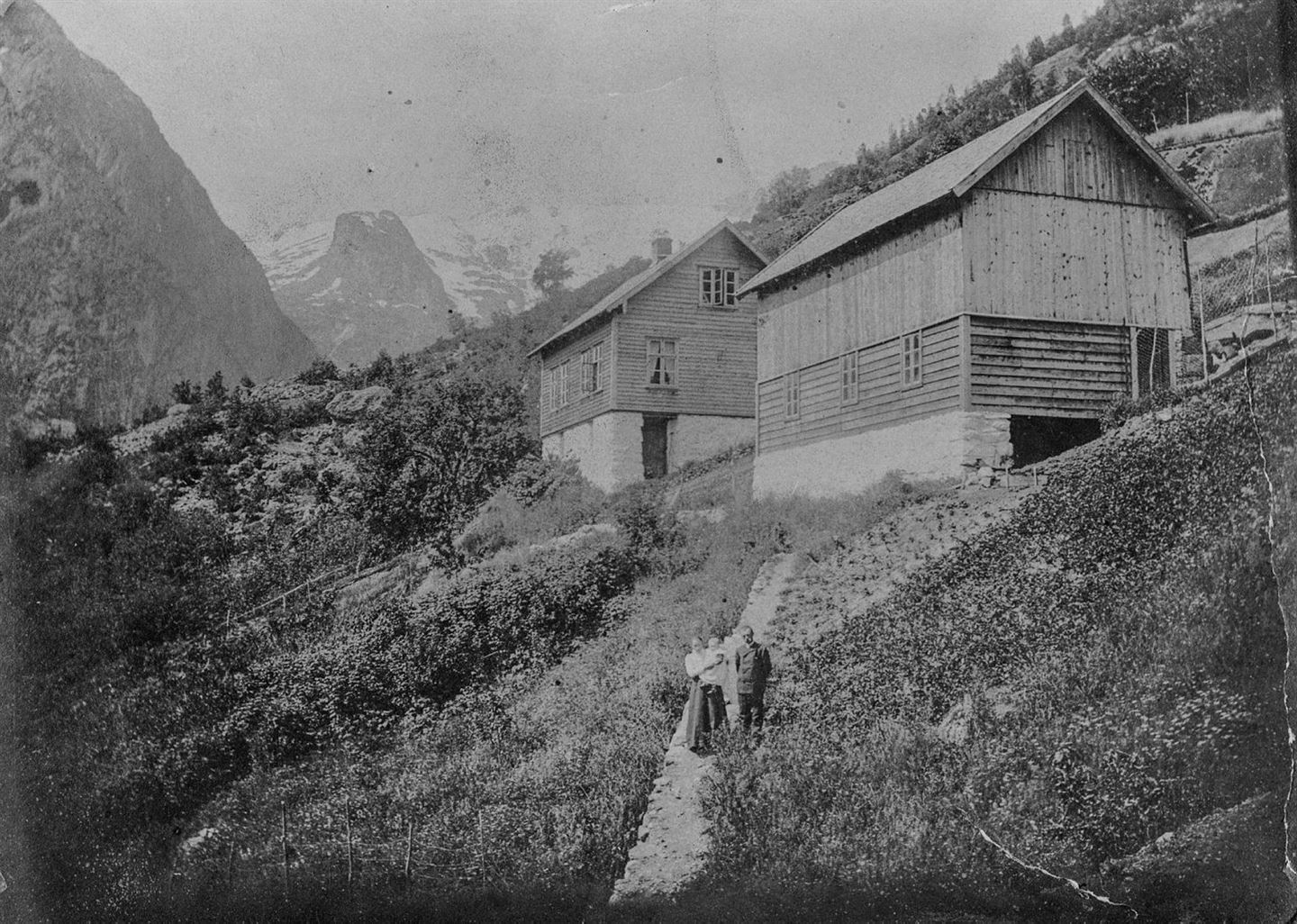 foto i svart kvitt av kvinne med barn på ein gard