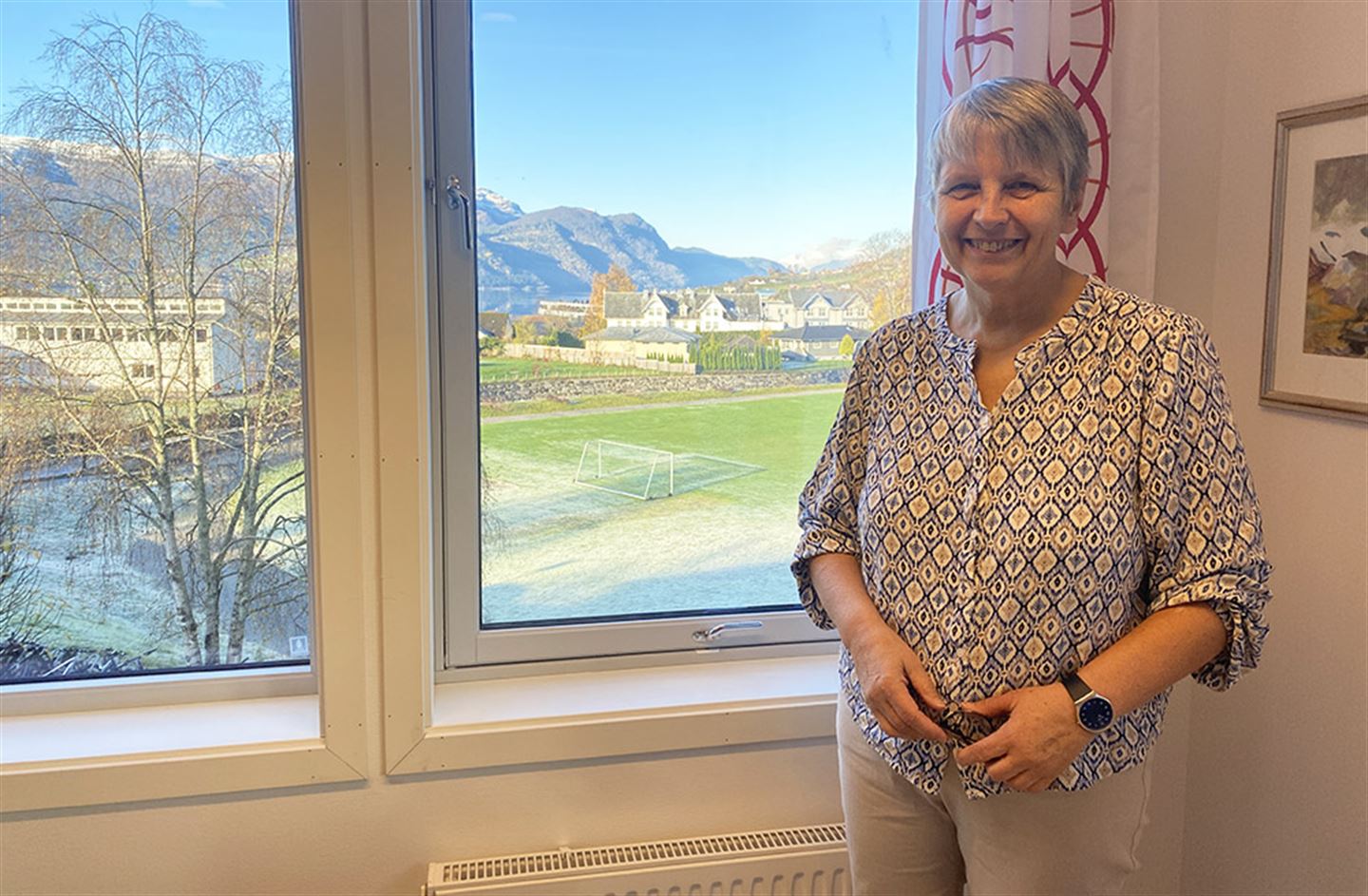 Berit Tesaker på rektorkontoret på Firda vgs., med utsikt til bygda, fjord og fjell.