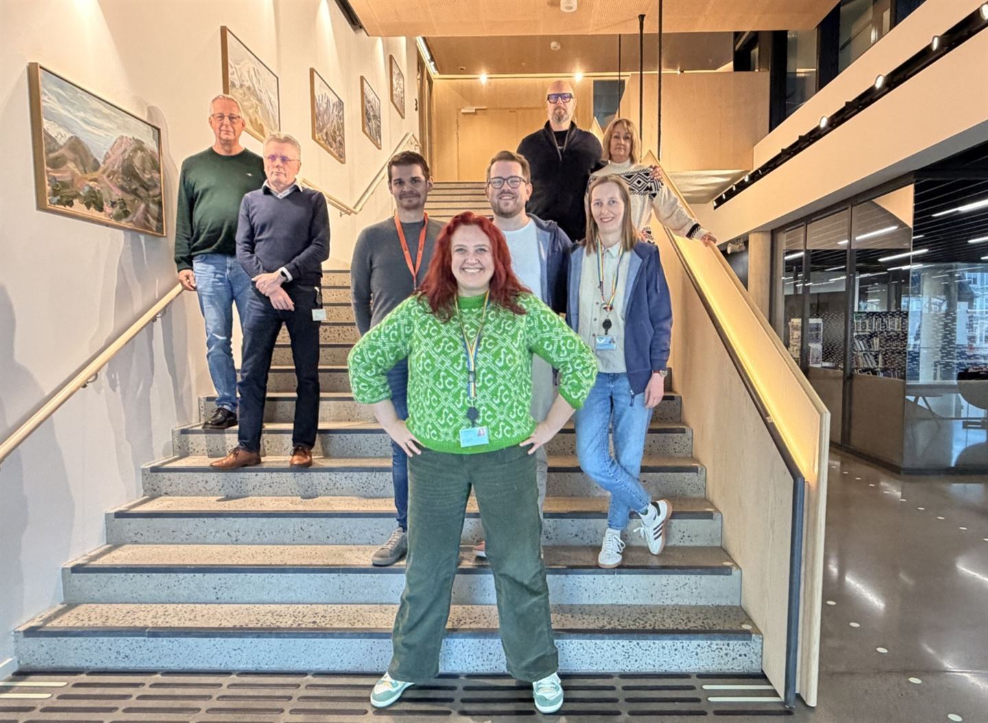 8 personer står gruppevis i ei trapp. 