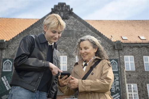 Ungdom som hjelper voksen dame med mobiltelefonen.