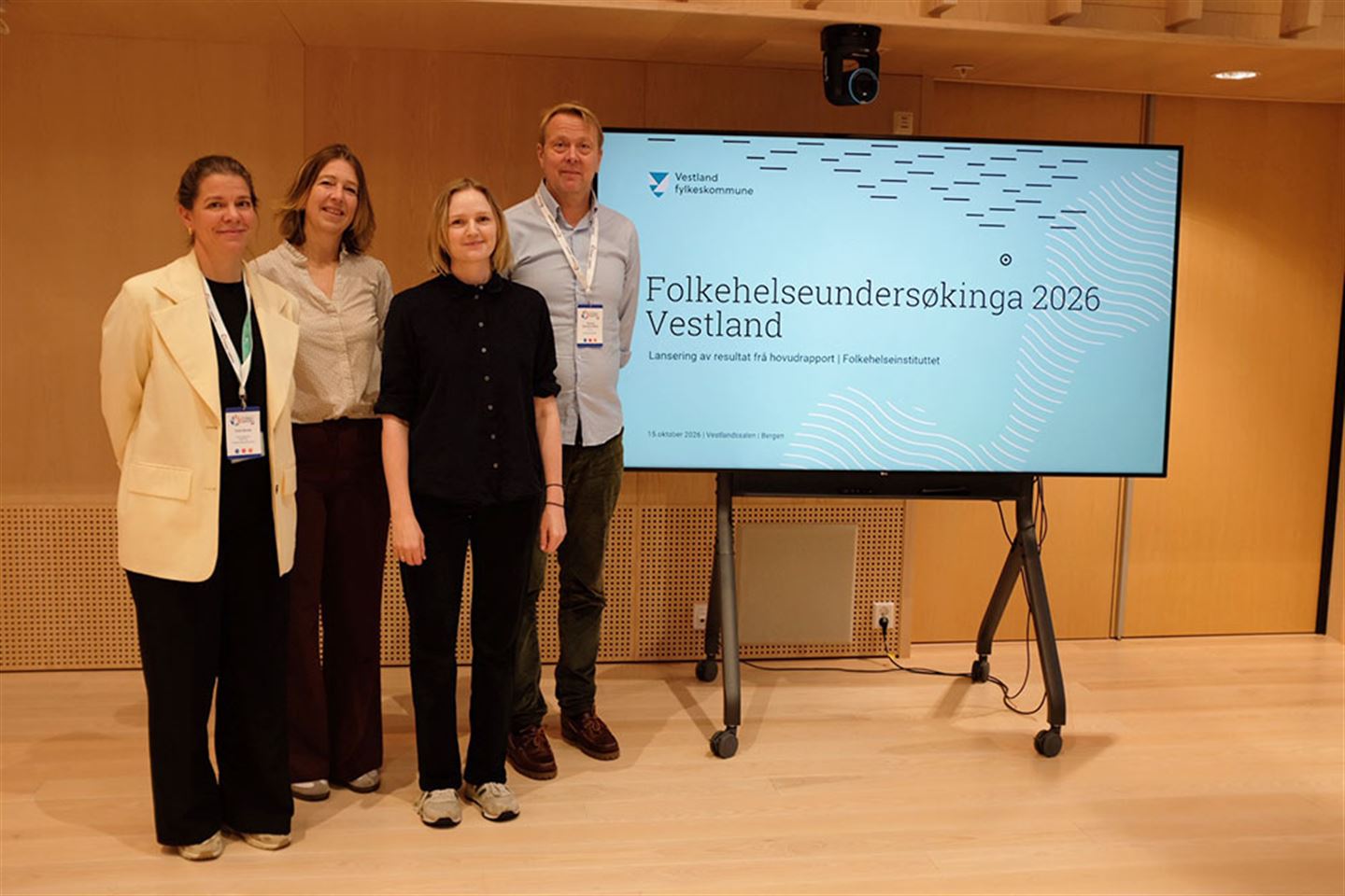 Tre kvinner og ein mann ved sidan av ein skjerm med teksten Folkehelseundersøkinga 2026 Vestland