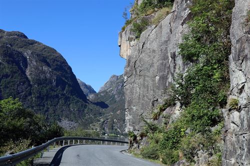 Smal veg som svinger seg rundt ein bratt fjellside. 