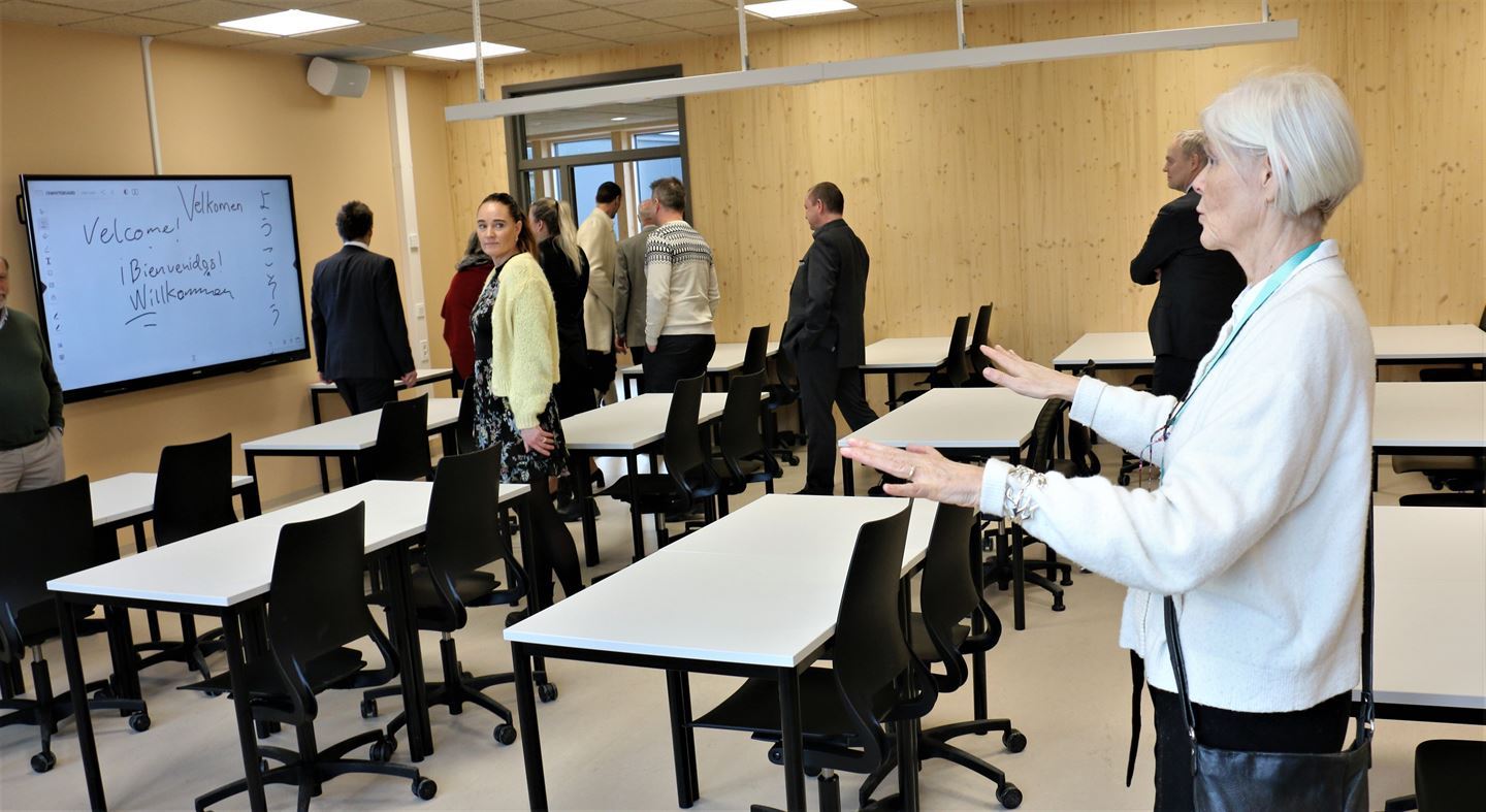 Kvinne i klasserom med ein del personar