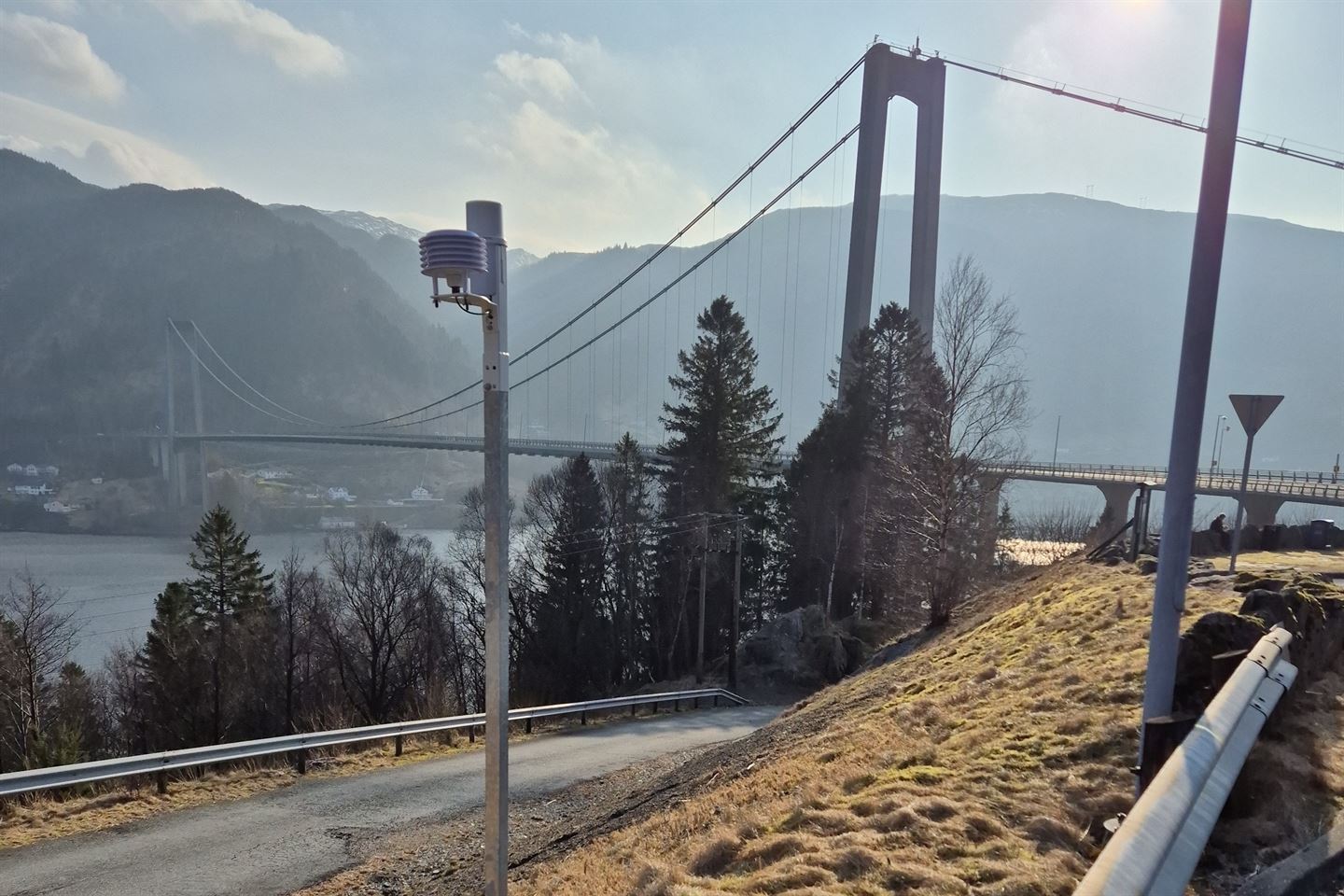 Ein klimastasjon på ein stang. bak er ei stor bru. 