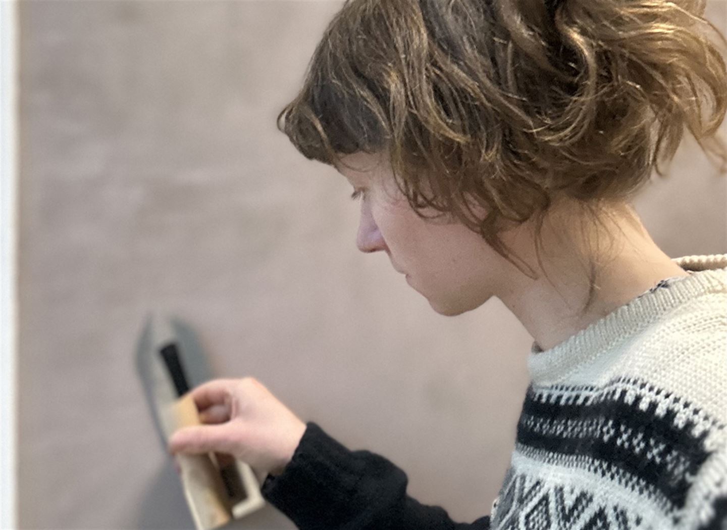 Kvinner pussar på vegg av leire.