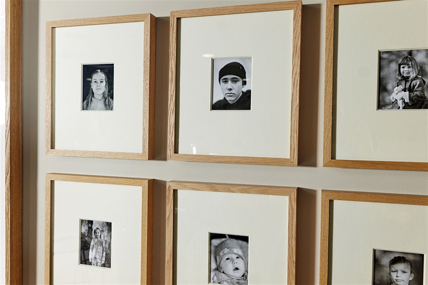 Små svart-kvitt portrettfotografi som heng på ein vegg.