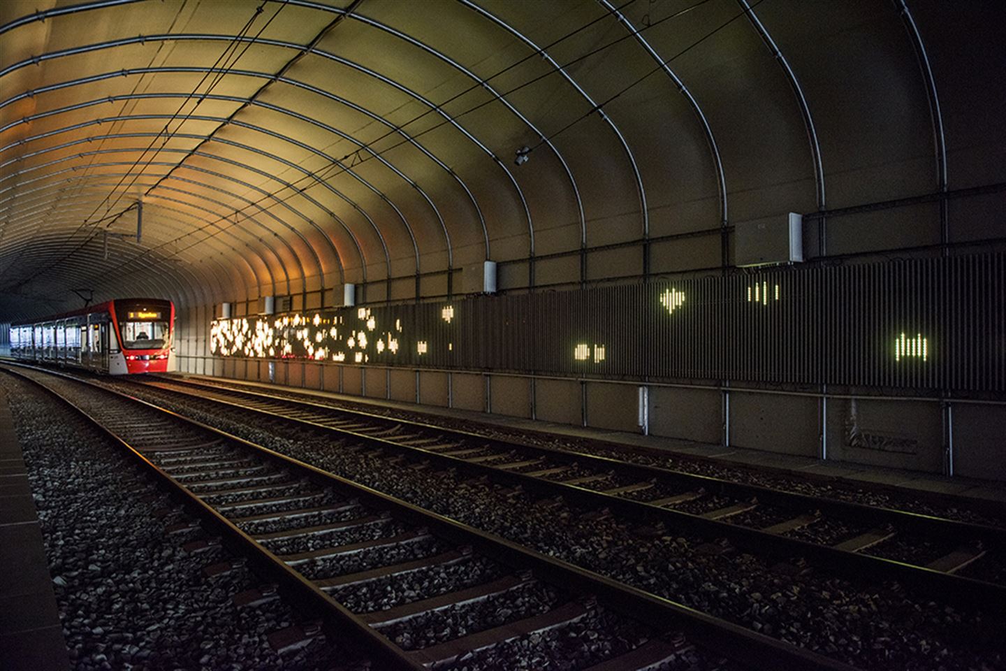 foto av kunstverket Kjankaren langs bybanetraseen. Det er gult lys på ein tunnelvegg.