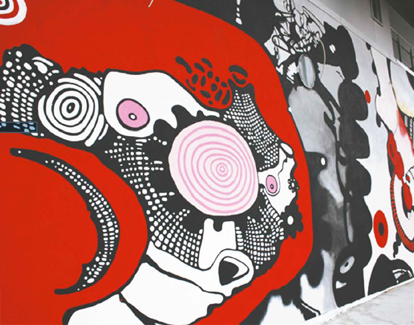foto av kunstverket Adebaran langs bybanetraseen. Det er eit stort teikneserieaktig kunstverkverk i svart, raudt og rosa.