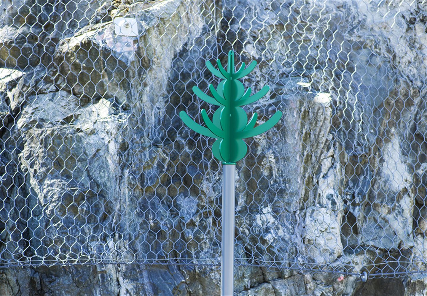 foto av kunstverket Olje-Norge langs bybanetraseen. Det er ein grøn figur festa øvst på ein stolpe.