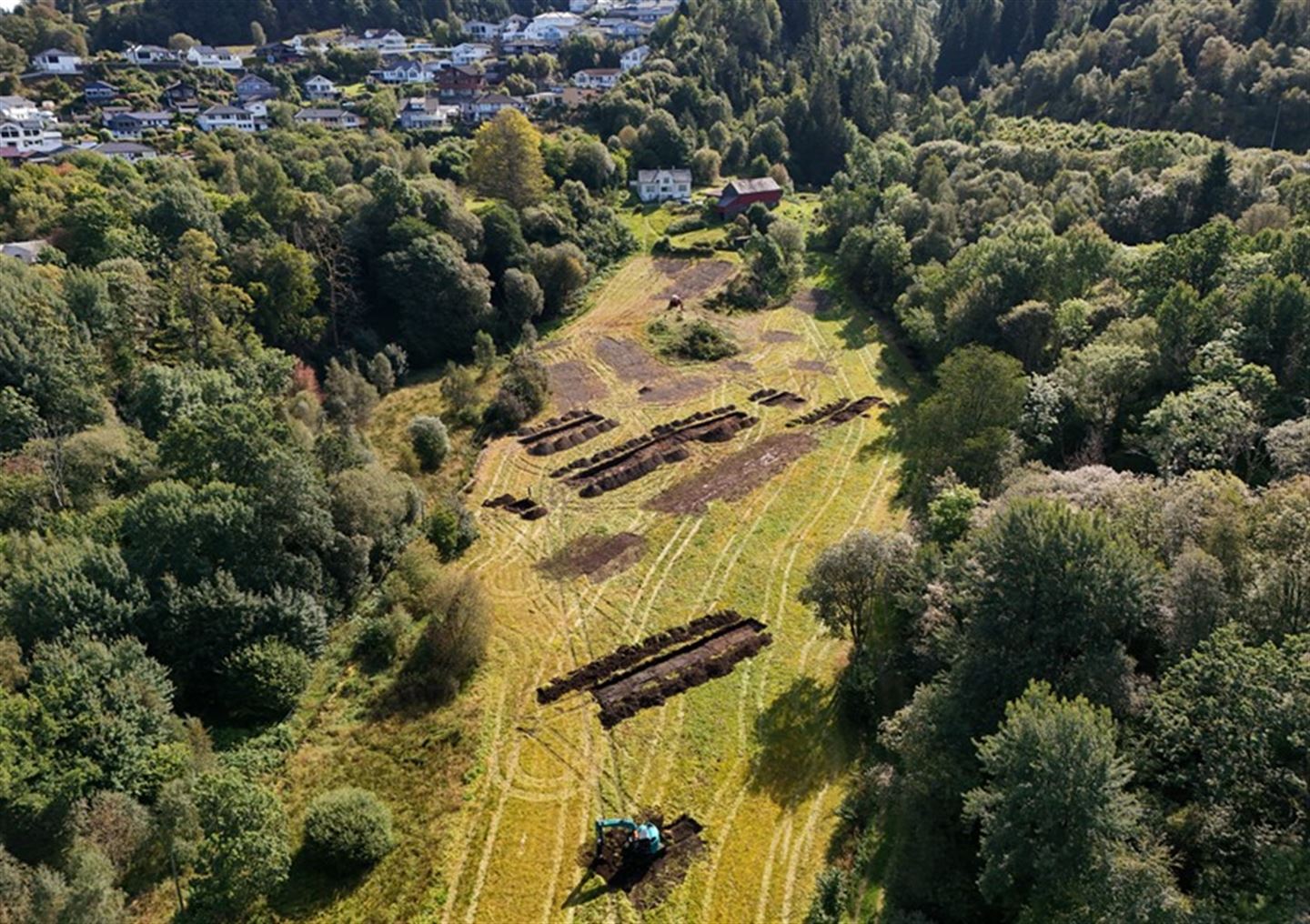 Dronebilde av sjakter på jorde i samband med arkeologisk registrering.