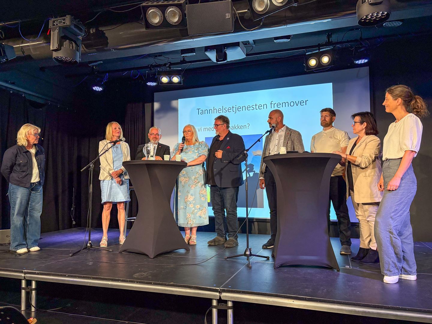 Ni personer står på en scene
