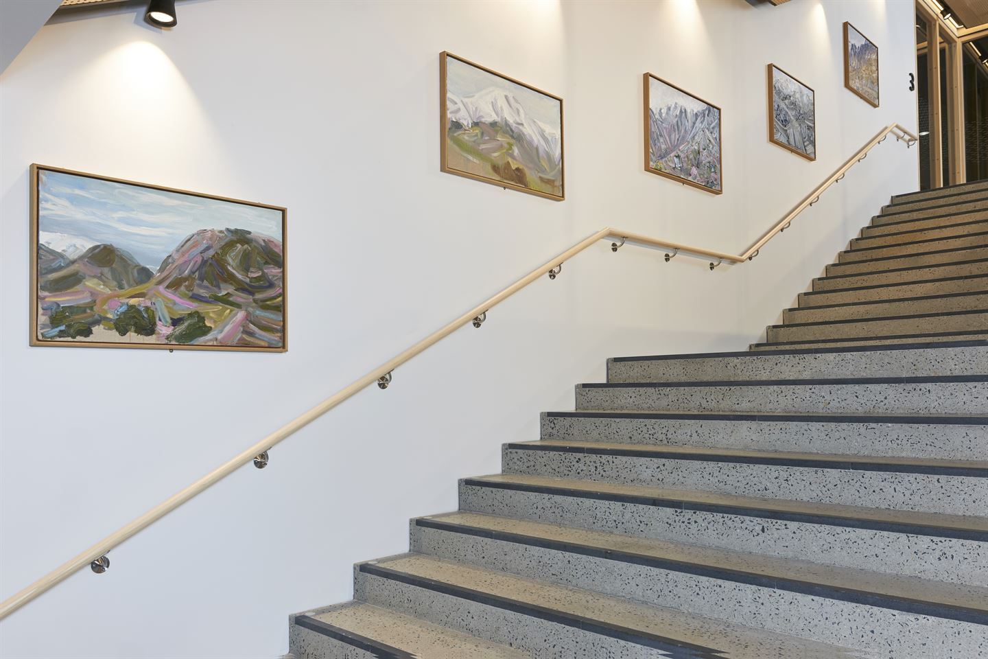 Foto av fem mindre maleri på veggen i trapp.