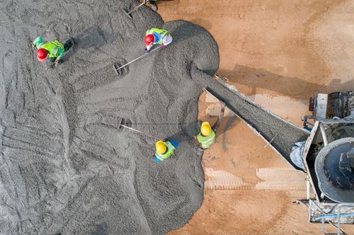 fugleperpektivbilde av tre arbeidere som heller betong over bakken