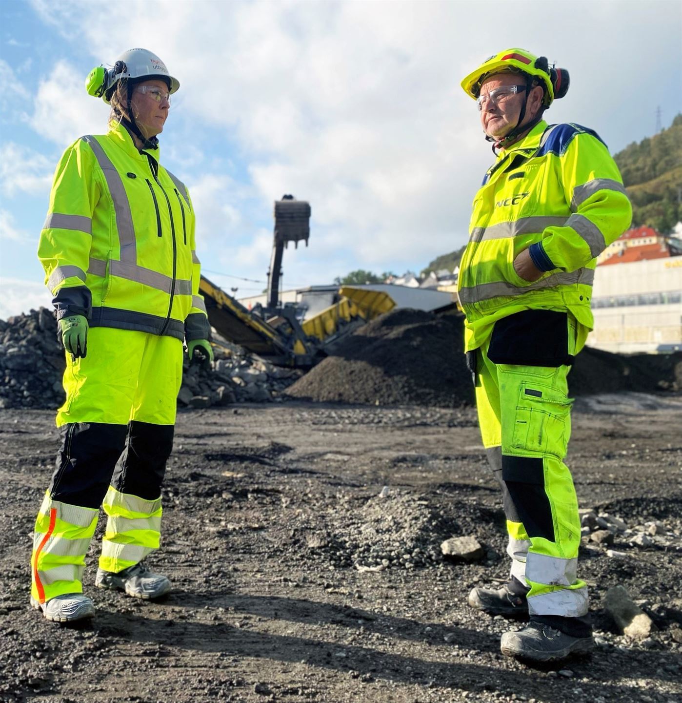 to personer i gult arbeidstøy og hjelm på byggeplass